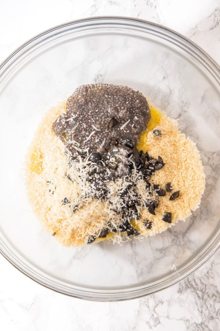Chia seed mixture, shredded cheese, chopped olives, and olive oil in bowl