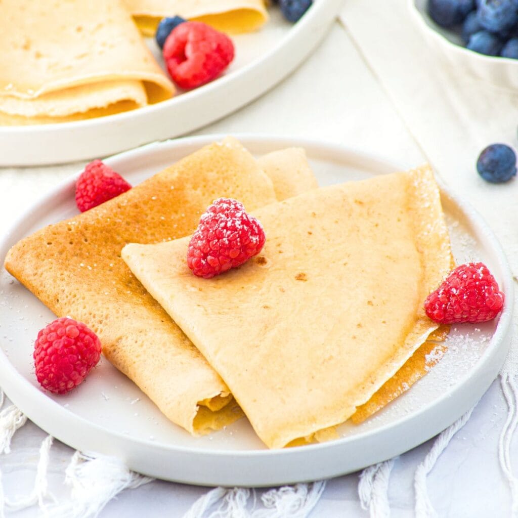 A plate of almond flour crepes topped with fresh raspberries