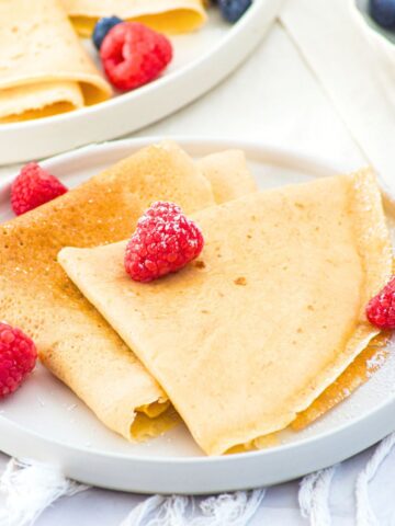 A plate of almond flour crepes topped with fresh raspberries
