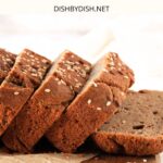 Up close view of a sliced loaf of bread on parchment-lined board.