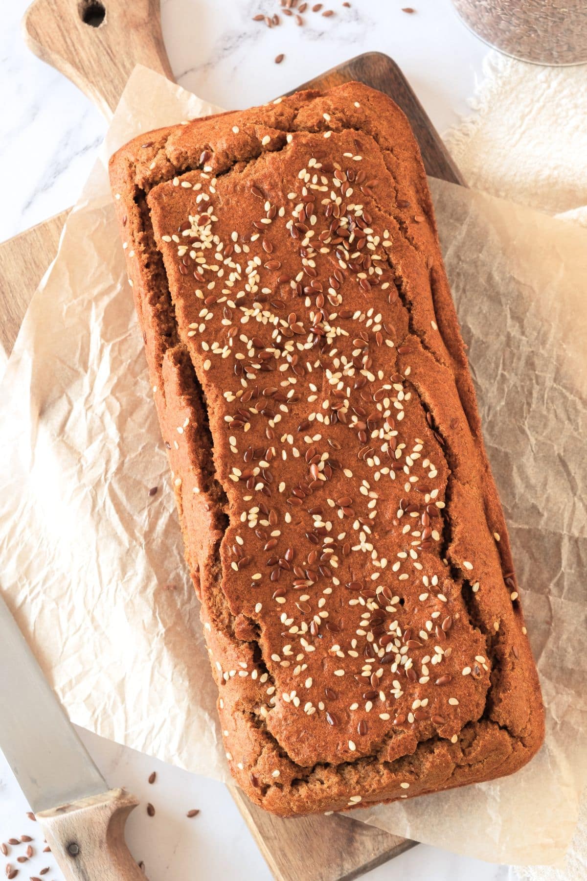 Top down view of freshly baked loaf of almond flax bread on parchment paper.