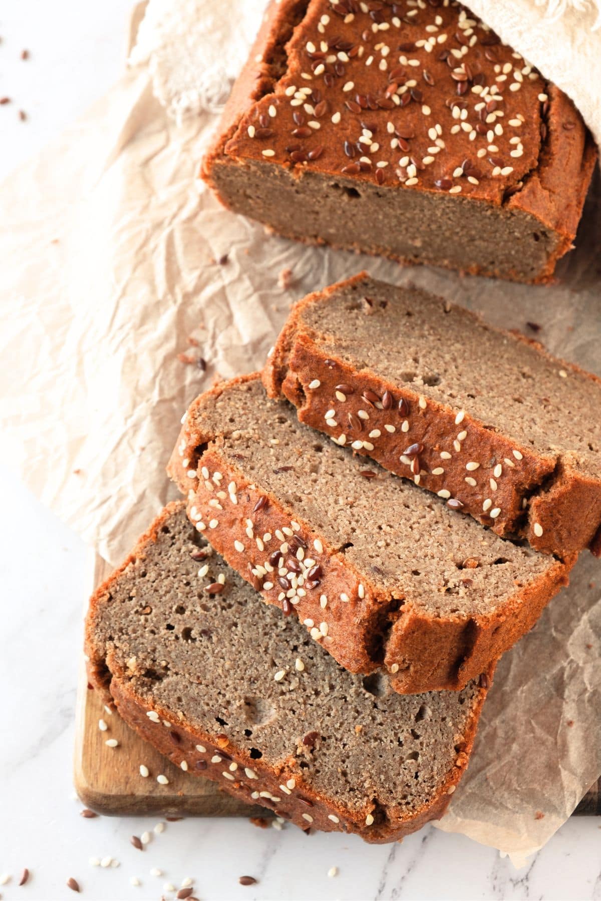 A sliced loaf of almond flour flaxseed bread on parchment paper.