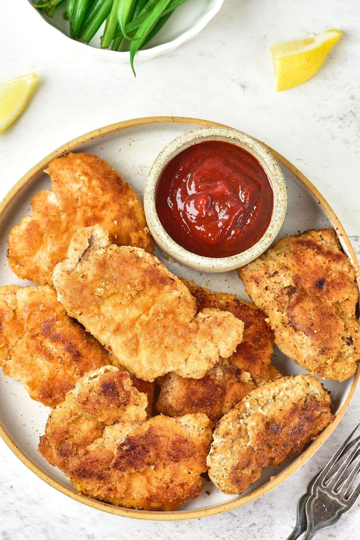 Top down view of a plate of crispy almond flour fried chicken and ketchup