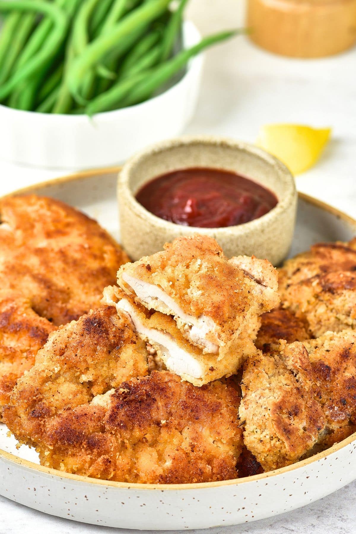 A plate of crispy almond flour chicken and ketchup