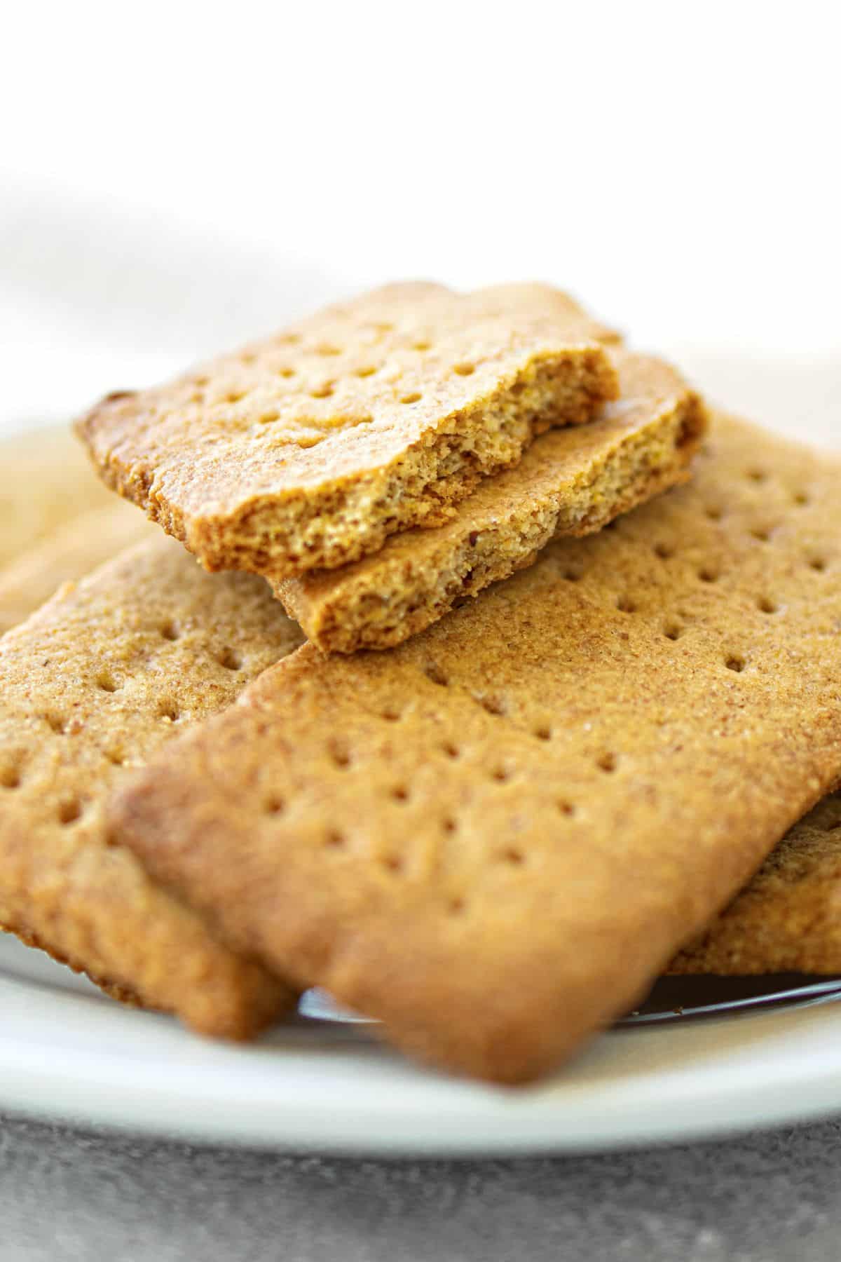 Up close view of a plate of half-eaten almond graham crackers.