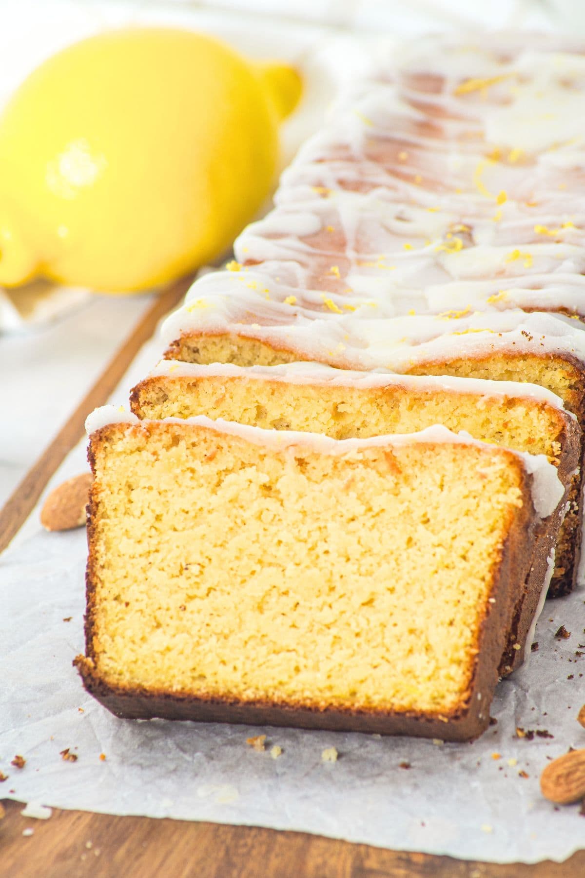 Half-sliced almond flour lemon loaf on parchment-lined board.