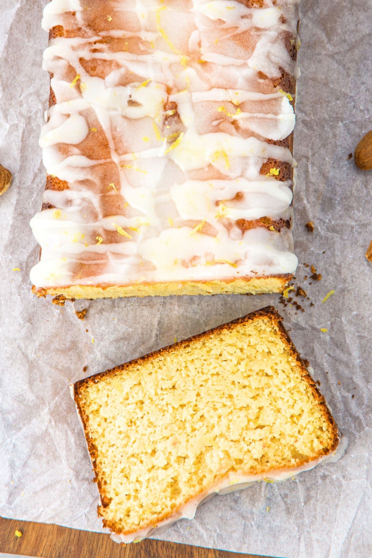 Slice almond flour lemon bread topped with lemon glaze on parchment