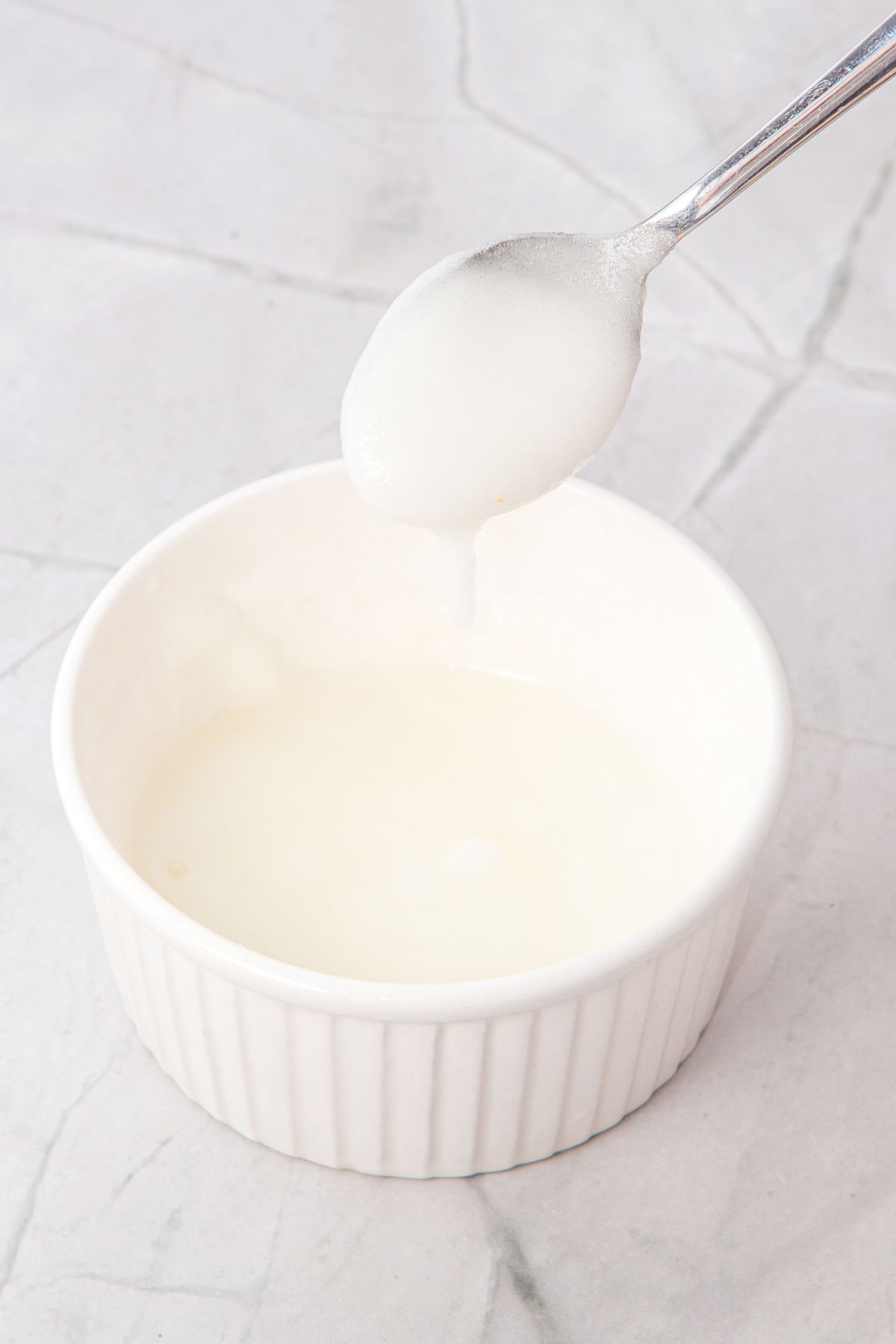 Holding up a spoonful of lemon glaze from ramekin