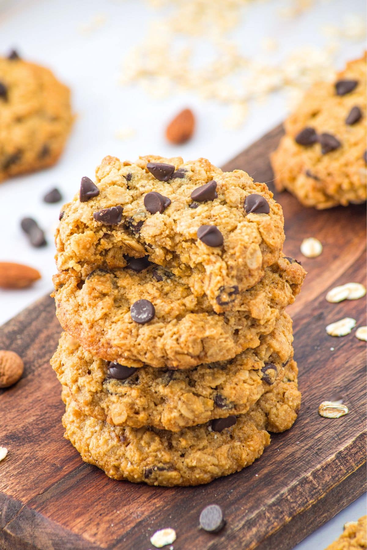 A stack of half-eaten almond flour and oatmeal cookies on wooden board.
