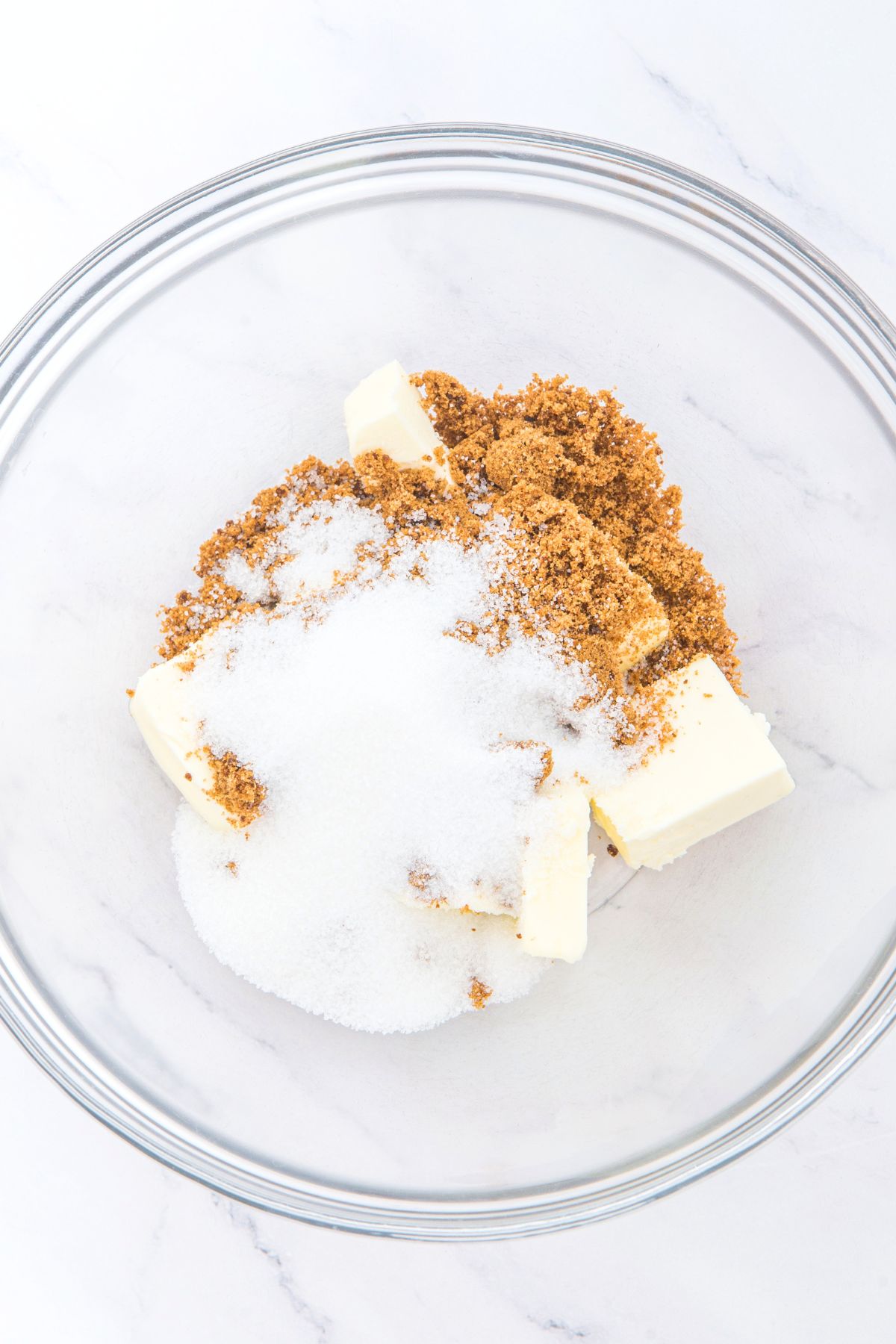 Cubed butter, white sugar and brown sugar in glass bowl