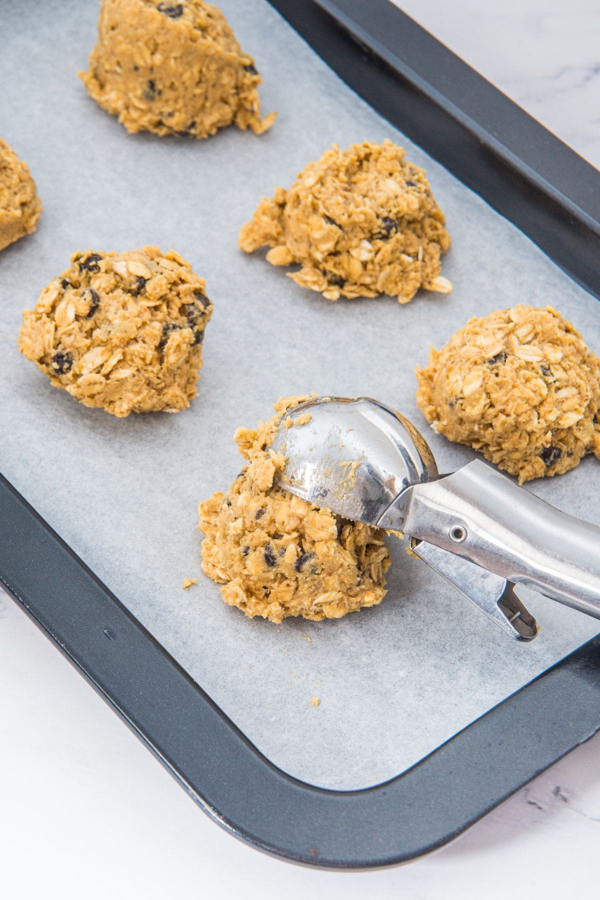 Scooping cookie dough onto parchment-lined baking sheet