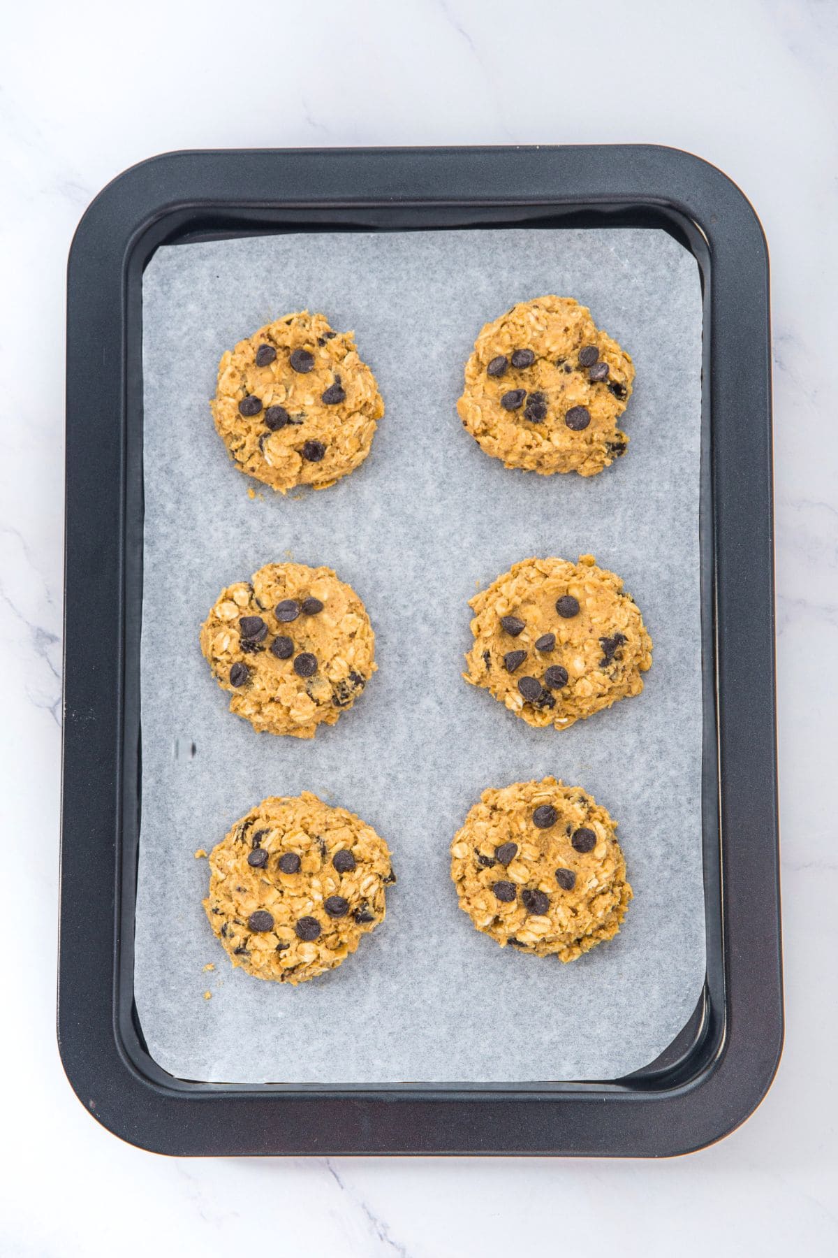 Top down view of raw cookie dough circles on parchment-lined sheet