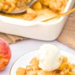 A small plate with peach cobbler topped with ice cream.