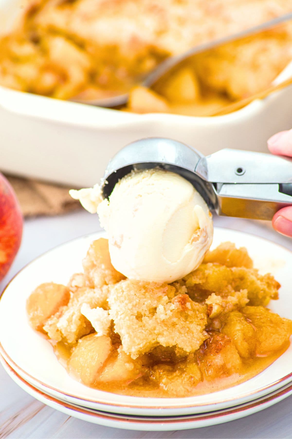 Peach Cobbler Made with Almond Flour Scooping ice cream on top of a plate of peach cobbler made with almond flour
