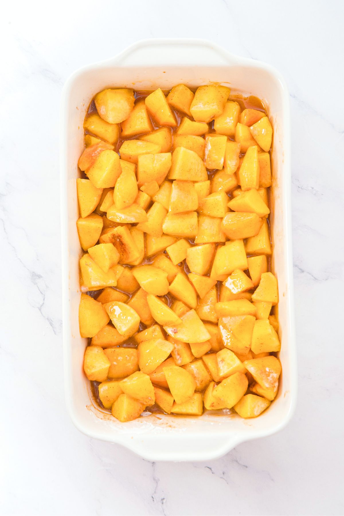 Gluten-Free Dairy-Free Peach Cobbler with Almond Flour Fresh cut peaches in baking dish