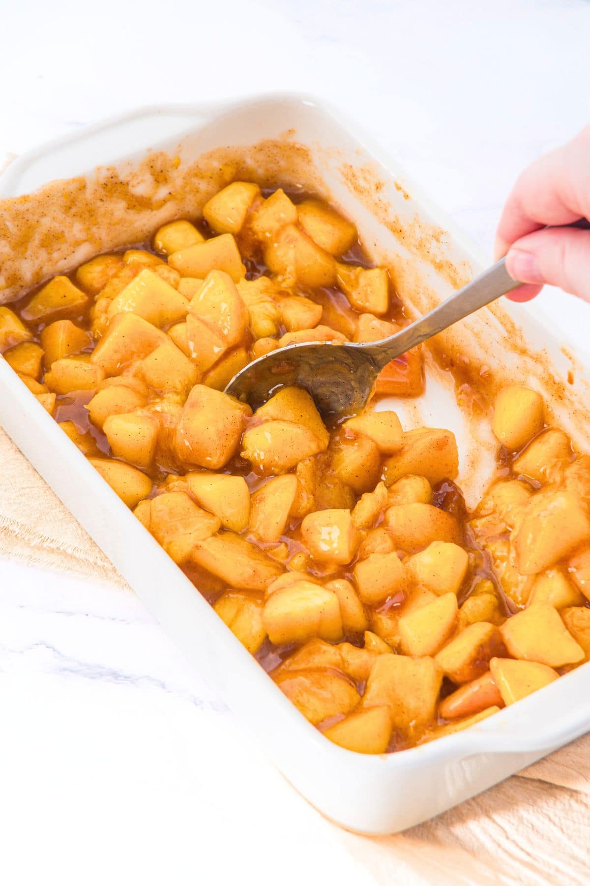 How to Make Almond Flour Peach Cobbler Mixing baked peaches in a baking dish