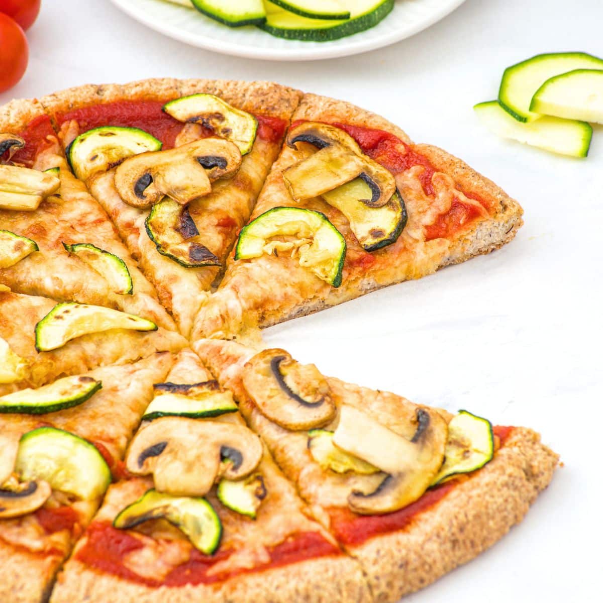 Half-eaten pizza with mushrooms and zucchini.