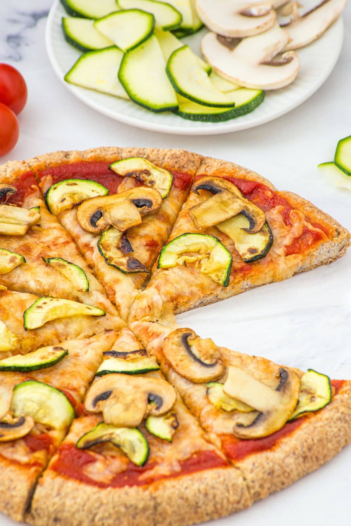 Up close view of almond flour pizza crust topped with mushrooms and zucchini
