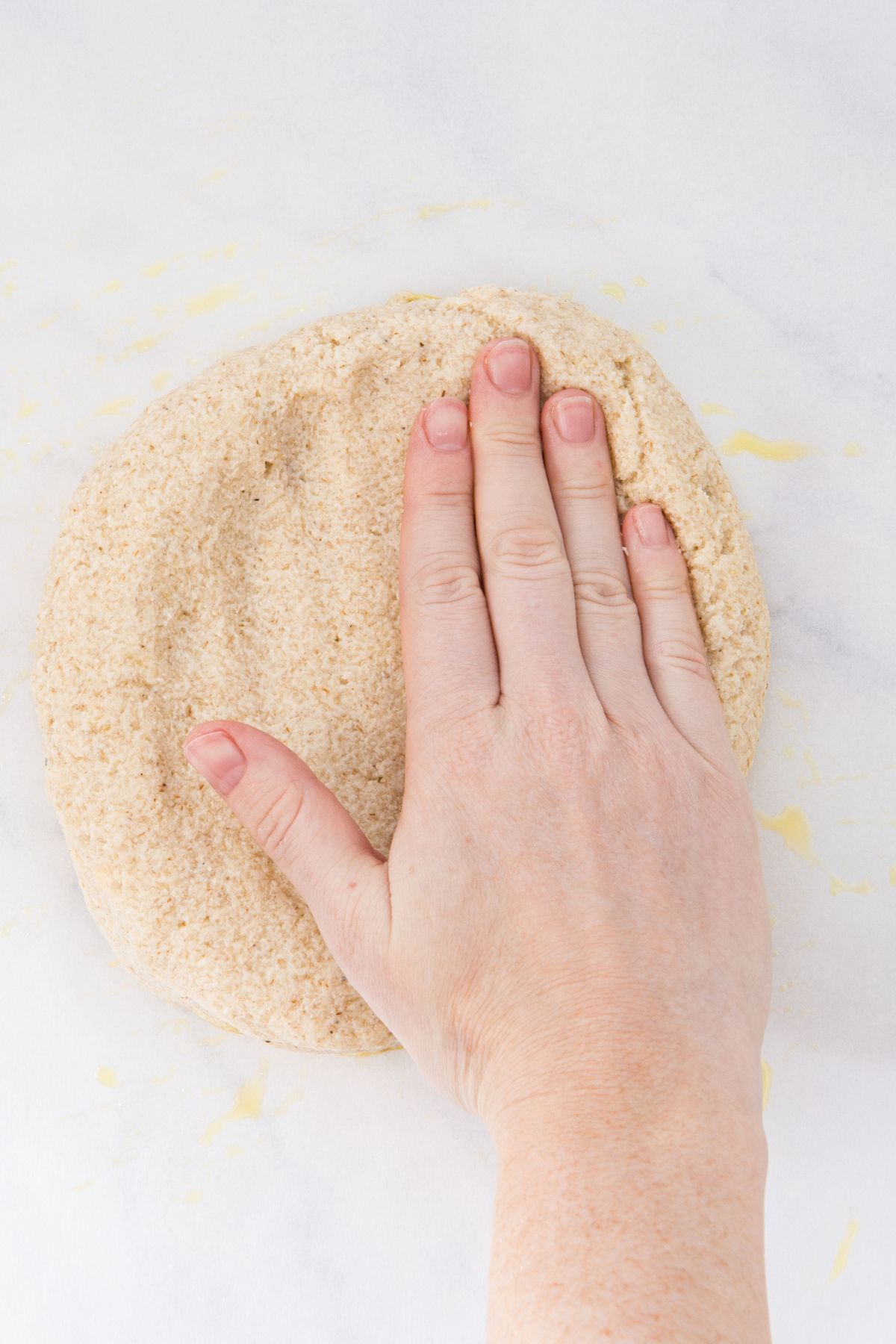 Hand pressing down onto pizza dough