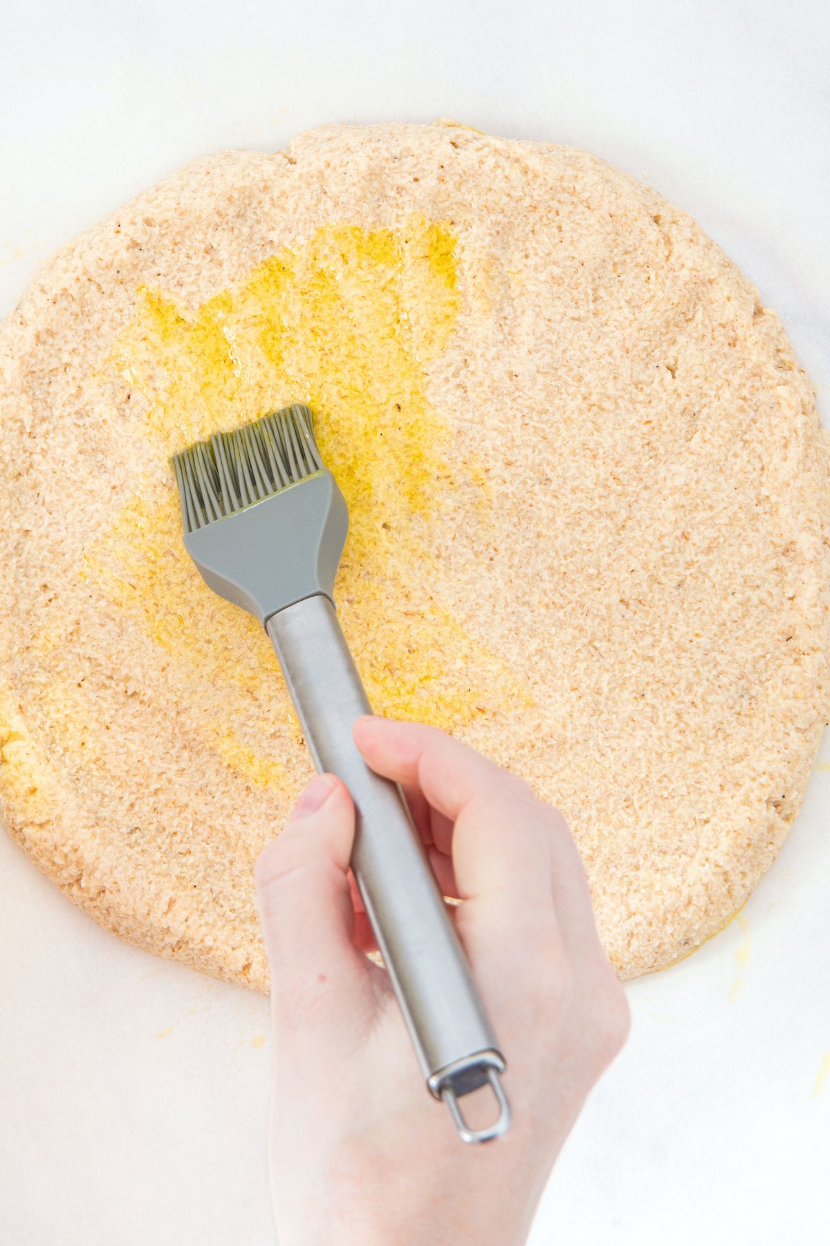 Brushing pizza dough with olive oil