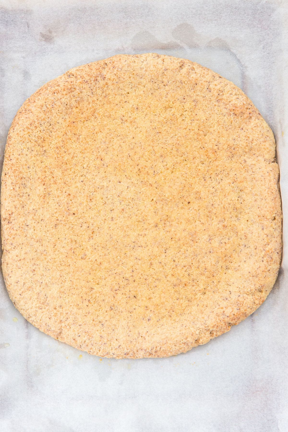 Baked pizza crust on parchment paper