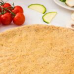 Almond flour pizza crust with cherry tomatoes behind