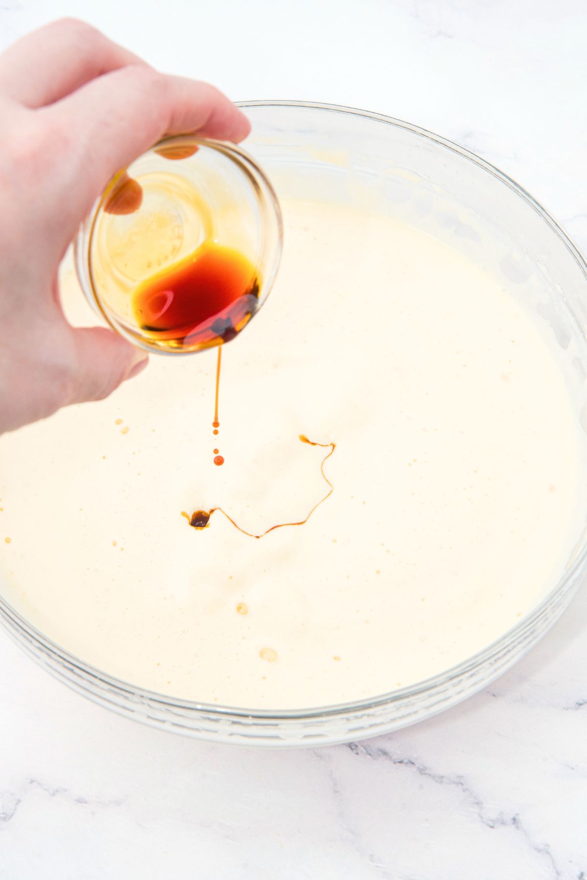 Pouring vanilla extract into batter.