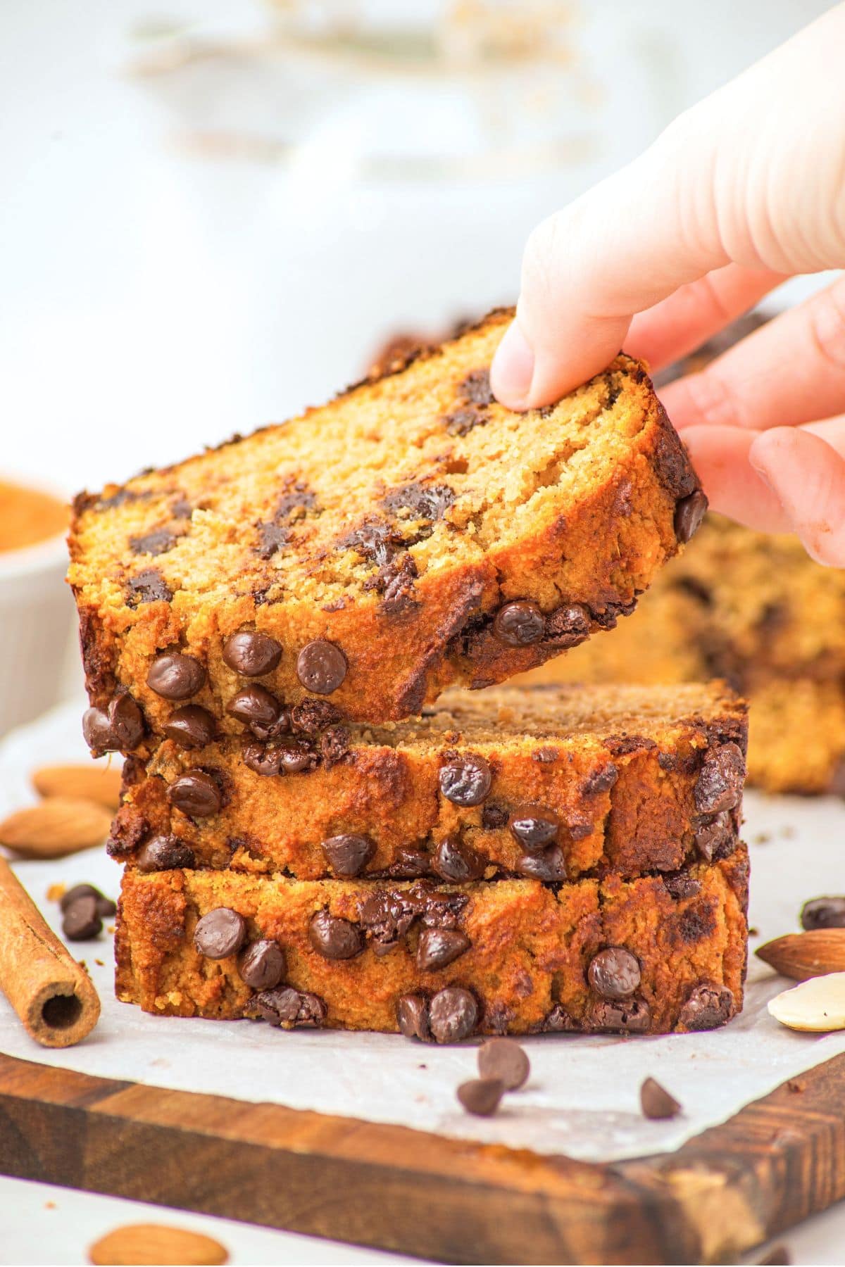 Almond Flour Pumpkin Bread (Gluten-Free, Dairy-Free) Hand reaching for a slice of moist almond flour pumpkin bread with chocolate chips.