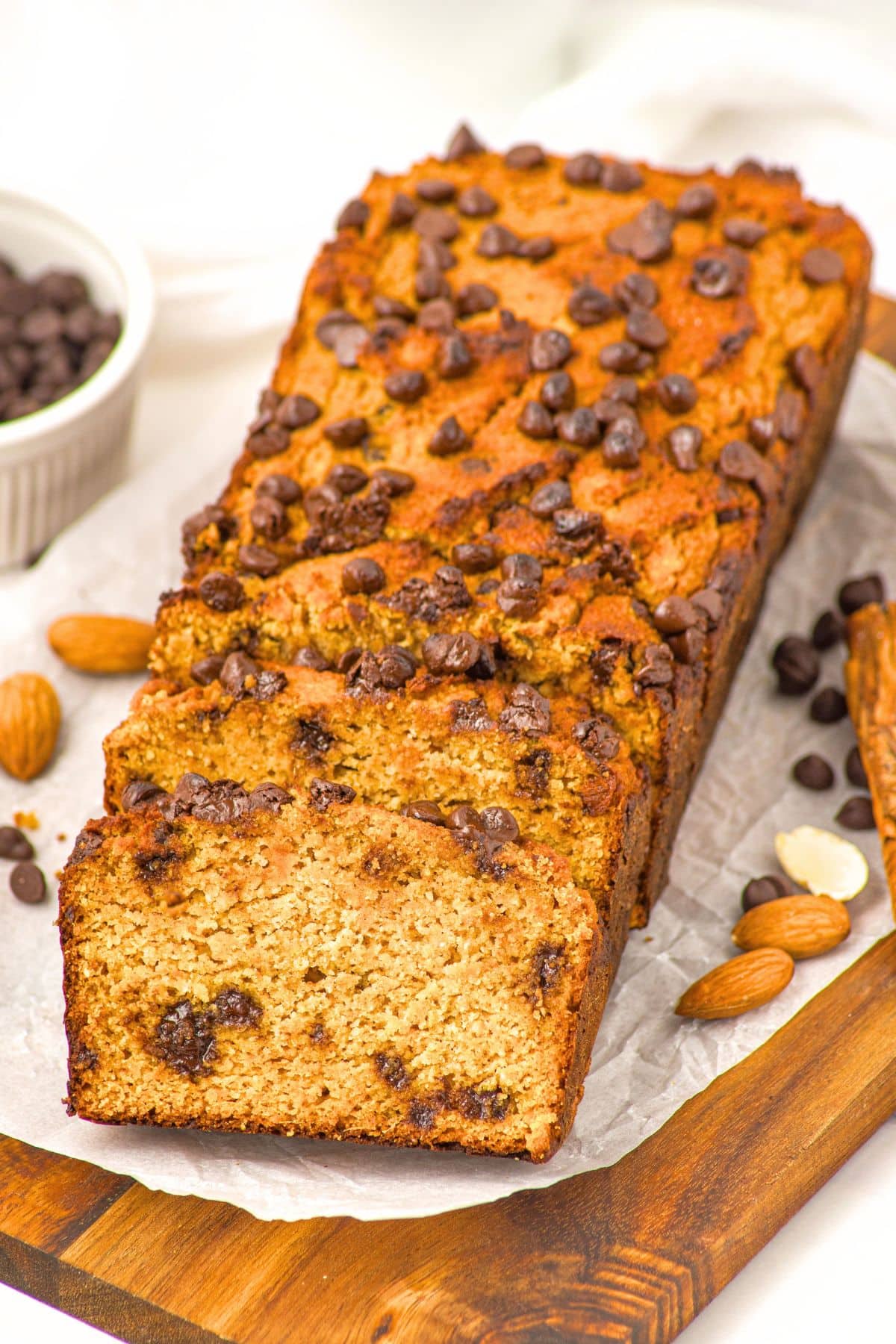 Grain-Free Pumpkin Bread with Almond Flour (Gluten-Free, Dairy-Free) A sliced loaf of grain-free pumpkin bread with almond flour on parchment-lined wooden board.