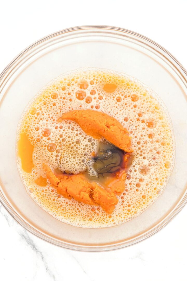 Pumpkin puree, eggs, honey and vanilla extract in glass mixing bowl.