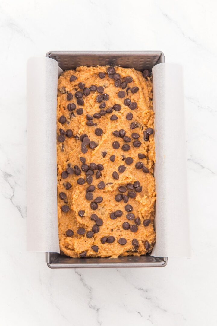 Almond flour pumpkin bread batter topped with chocolate chips in loaf pan.