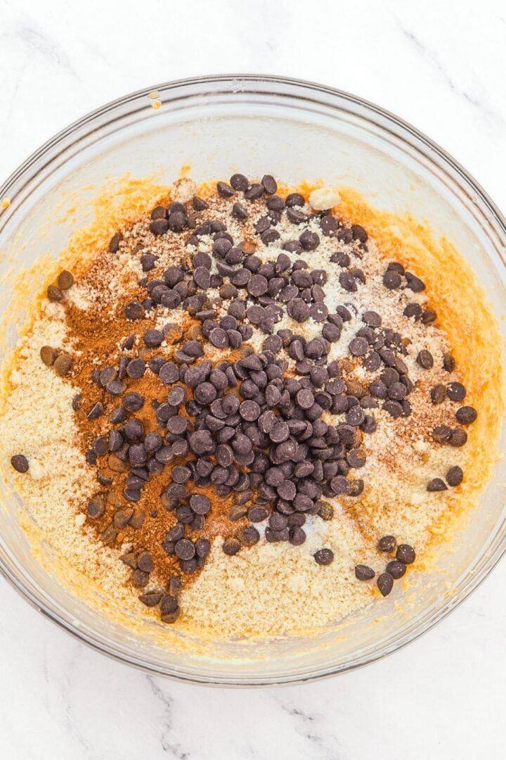 Almond flour, spices, and chocolate chips on top of orange batter.