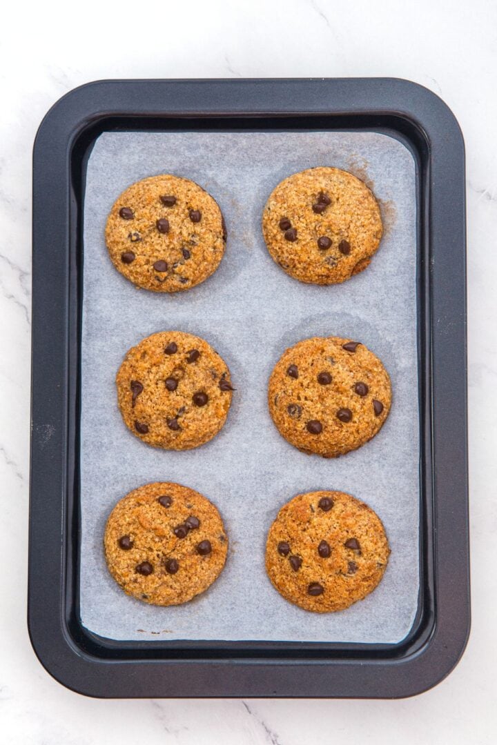 Freshly baked almond flour pumpkin cookies on parchment-lined baking sheet.