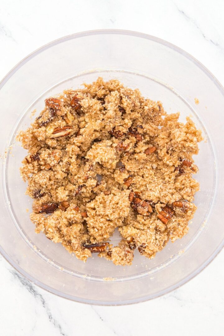 A glass bowl with brown almond flour mixture and pecans