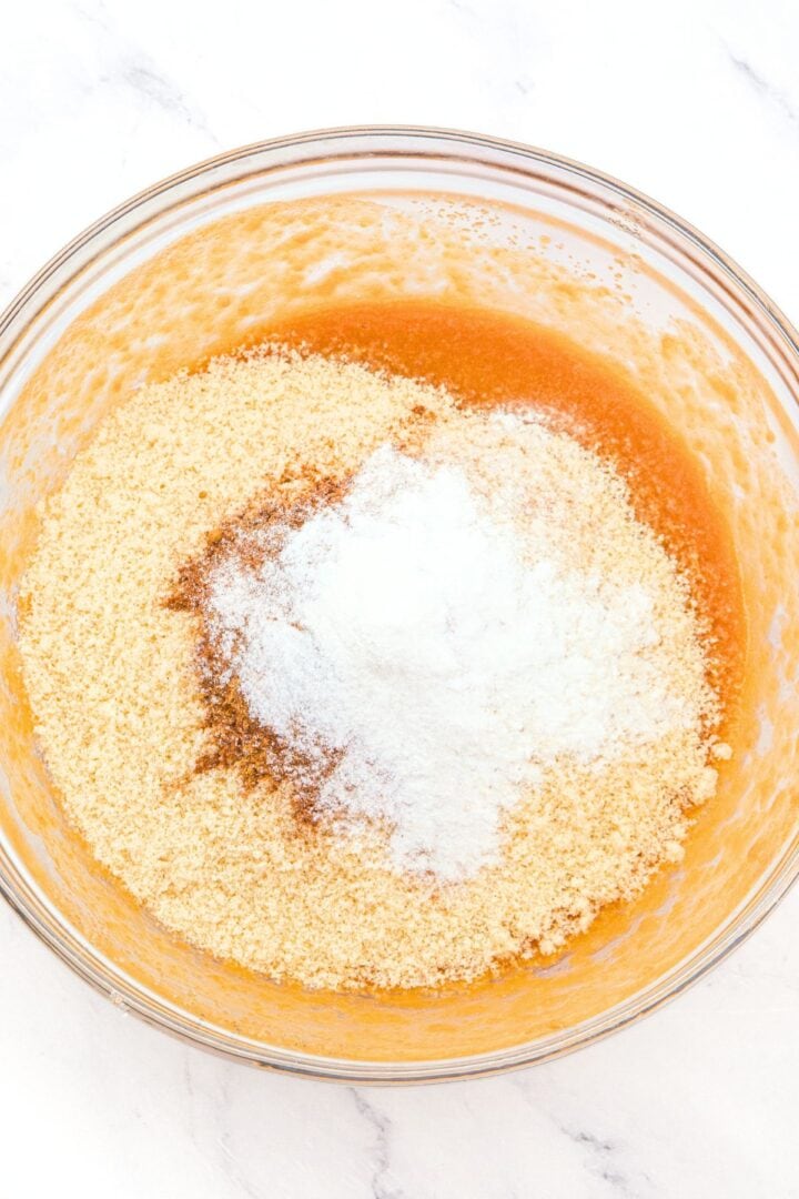 Blanched almond flour and baking powder on top of orange liquid mixture.