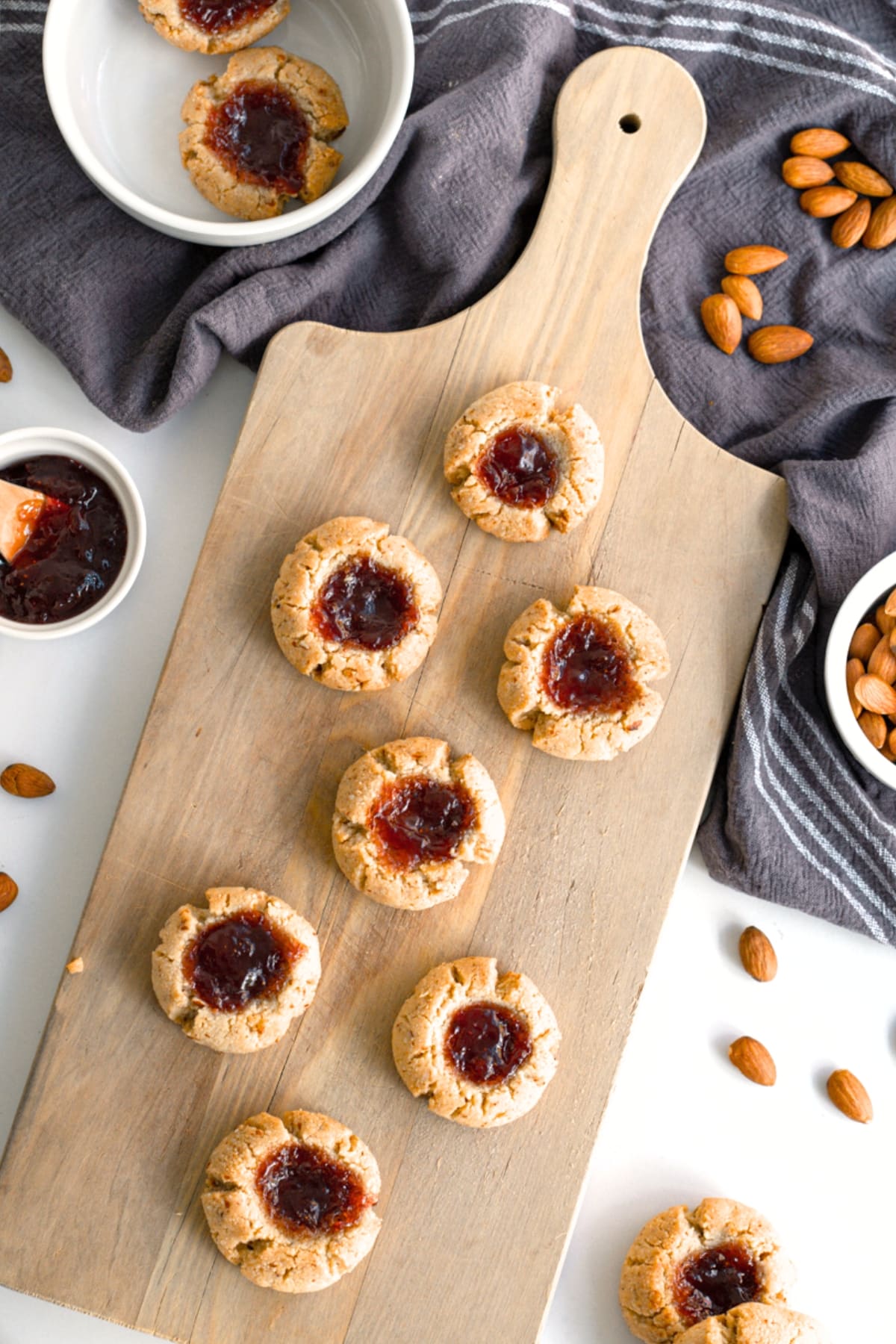 Top down view of thumbprint cookies with almond flour on wooden board.