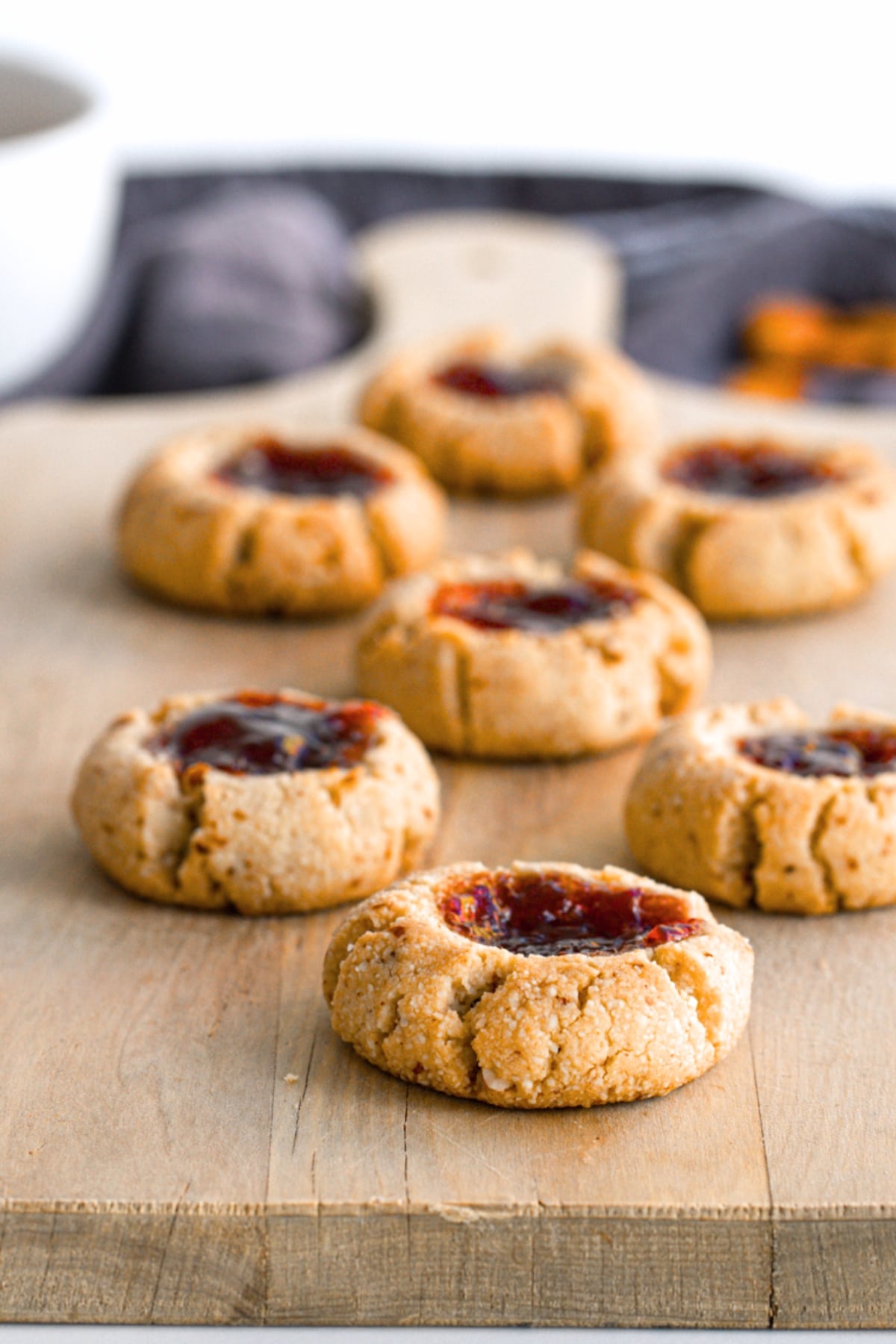 Up close shot of thumbprint cookies on wooden board.