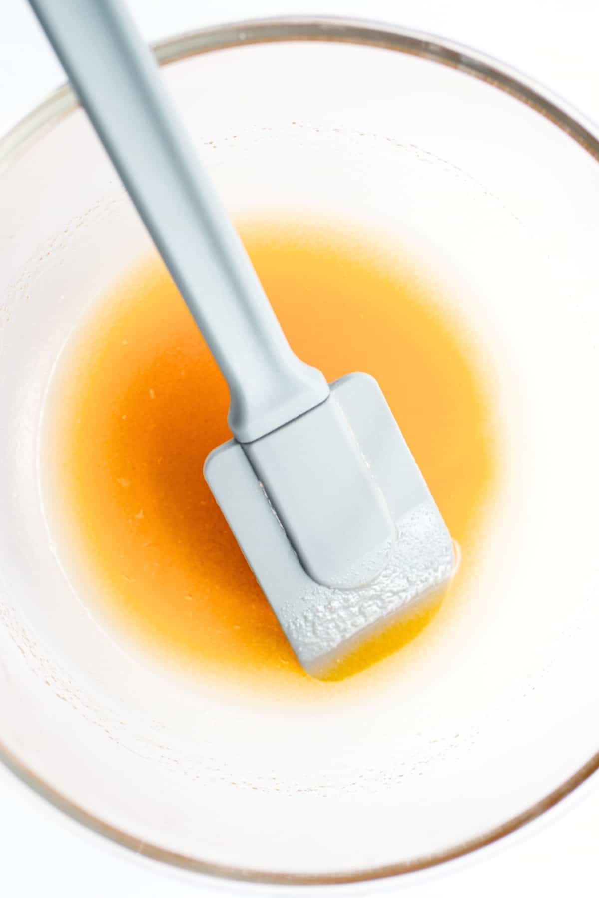 Mixing a yellow liquid mixture with a spatula.