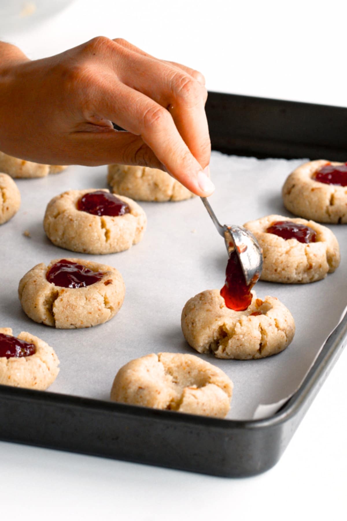 Filling thumbprint cookies with berry jam.