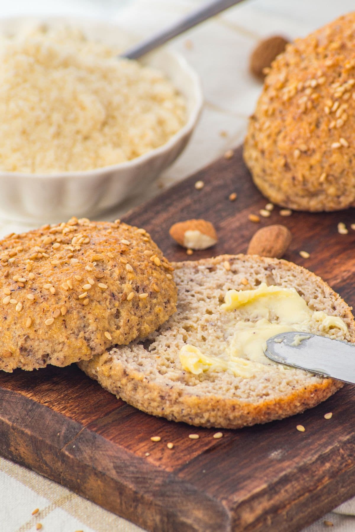 Spreading butter onto a sliced almond flour bun