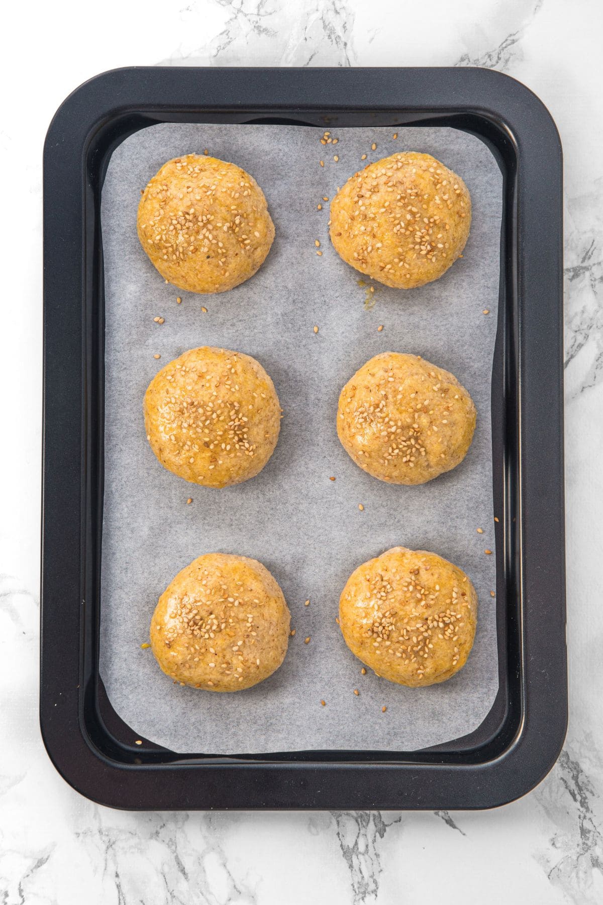 Balls of bread dough on parchment-lined baking sheet