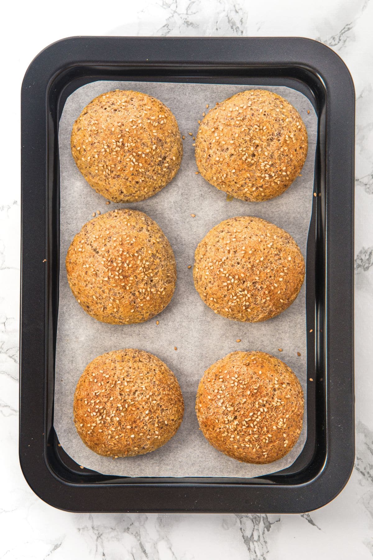 Freshly baked almond flour keto rolls on parchment-lined baking sheet