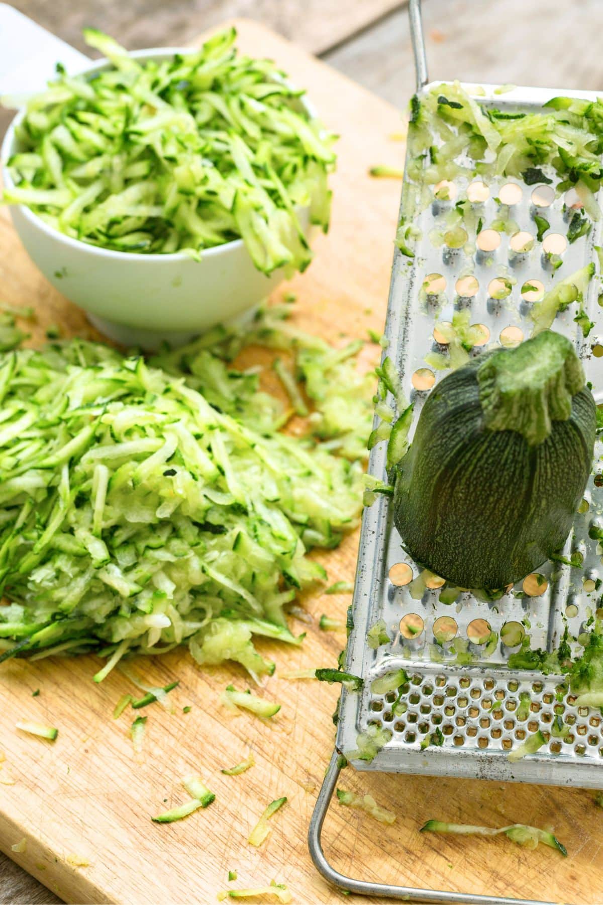 Grating fresh zucchini on wooden board