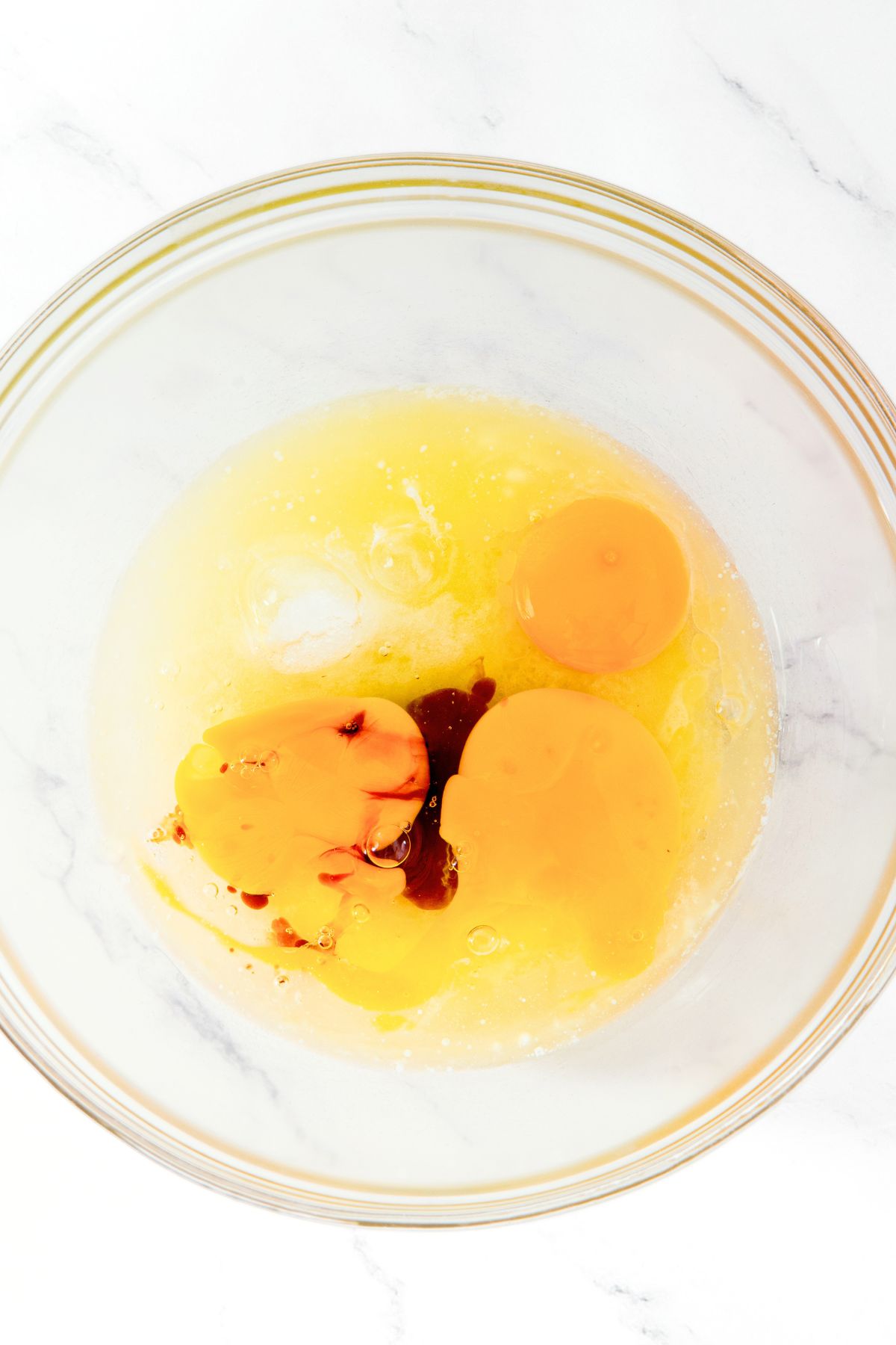 Eggs, melted butter and vanilla extract in bowl.