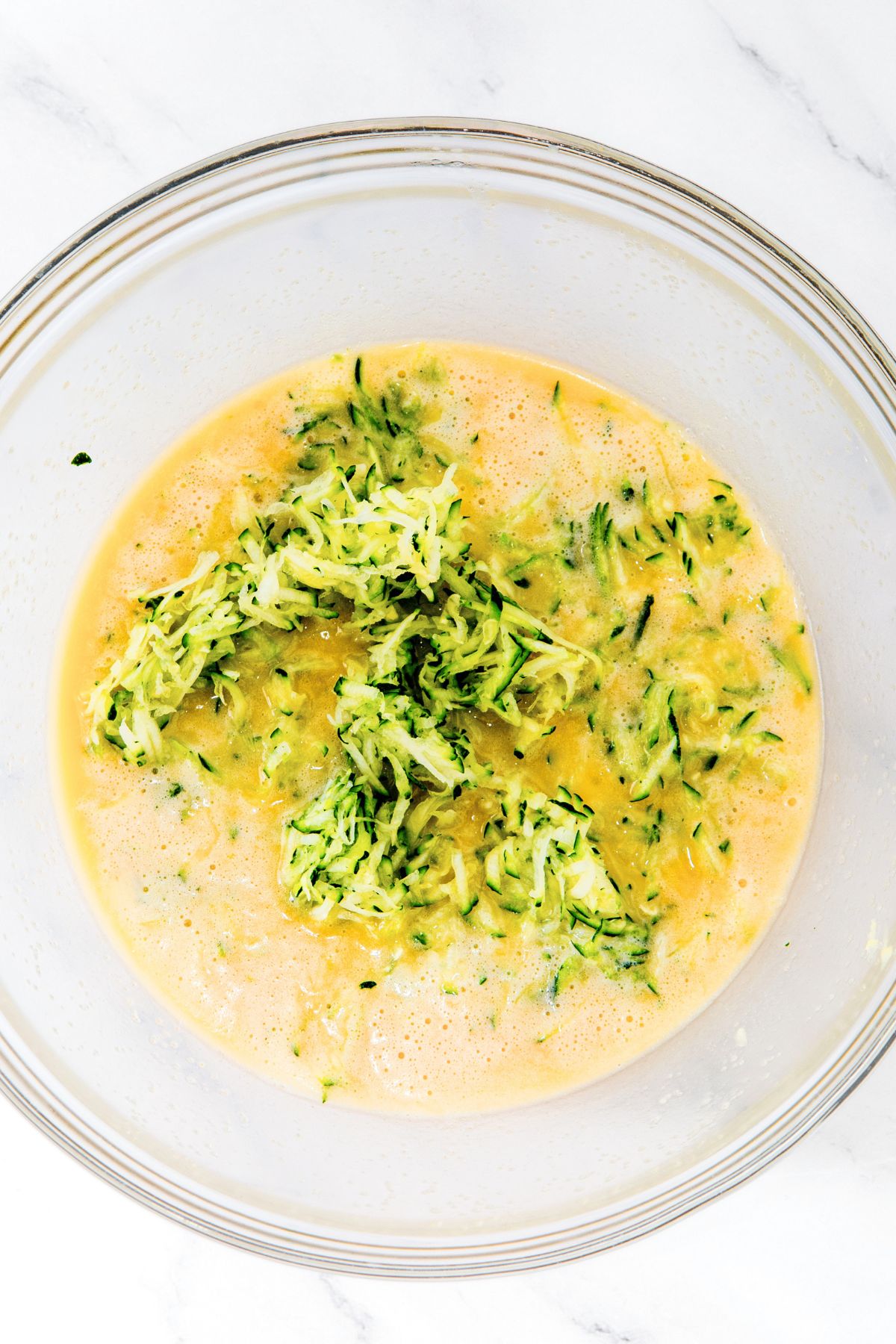 Grated zucchini in yellow liquid mixture