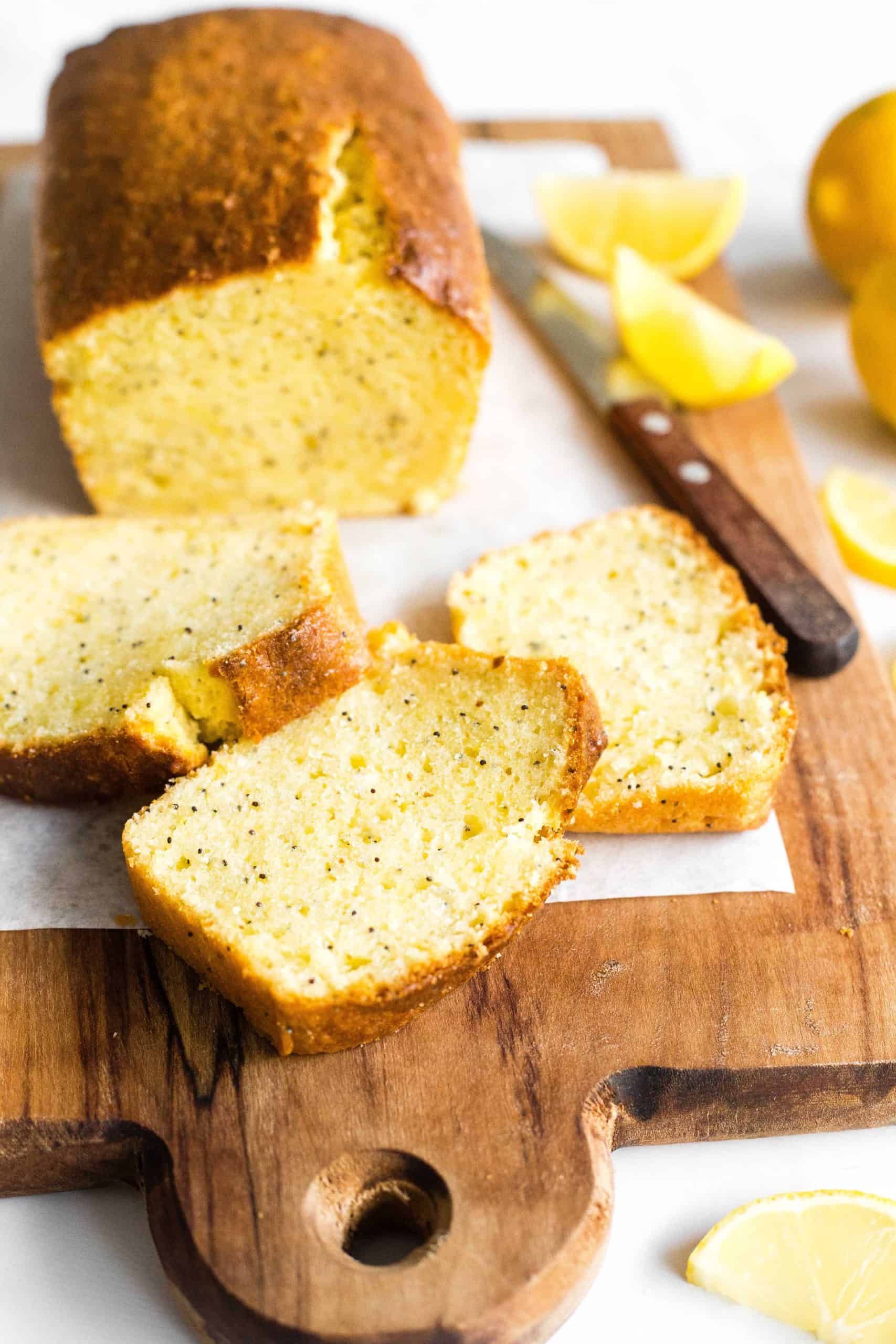 Slices of gluten-free lemon poppy seed bread on a parchment-lined wooden board.