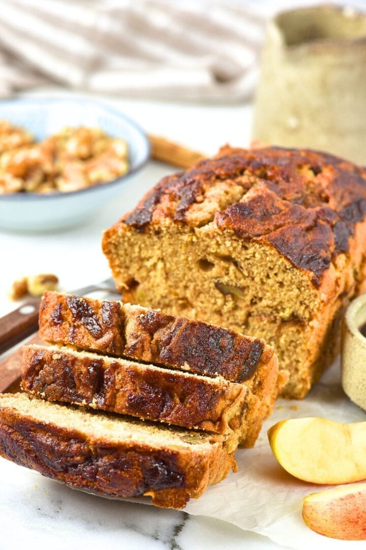 Sliced apple butter loaf on parchment-lined marble board.