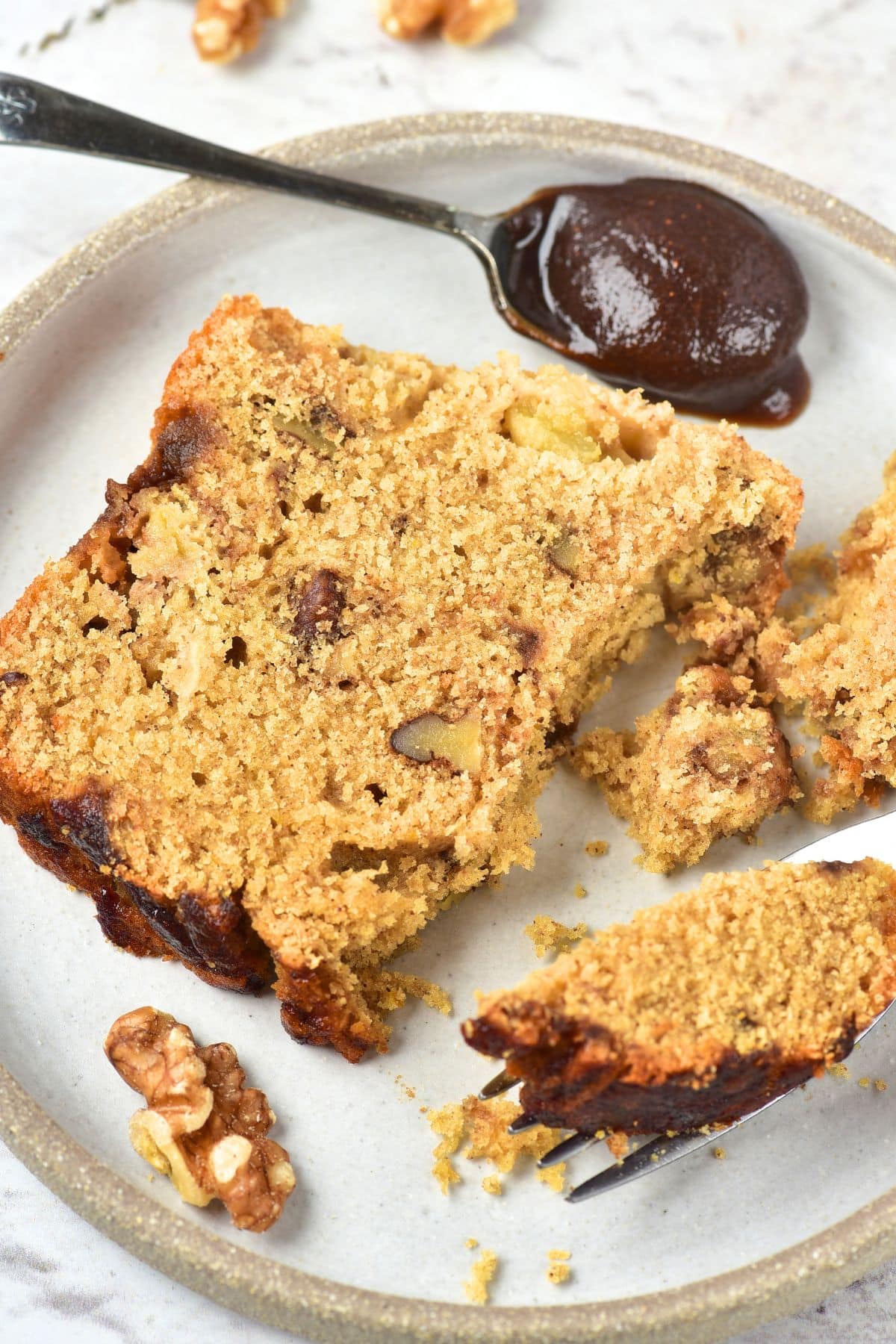 A slice of apple butter loaf interlaced with walnuts on a plate
