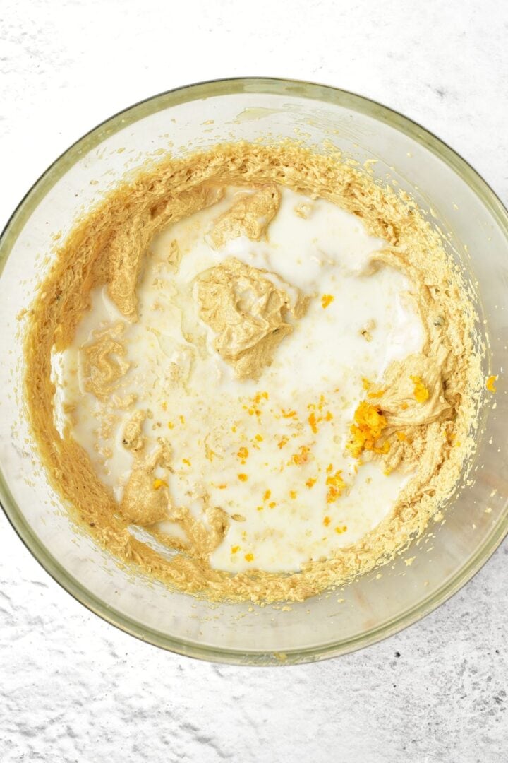Milk, vanilla extract and orange zest on top of light brown batter.