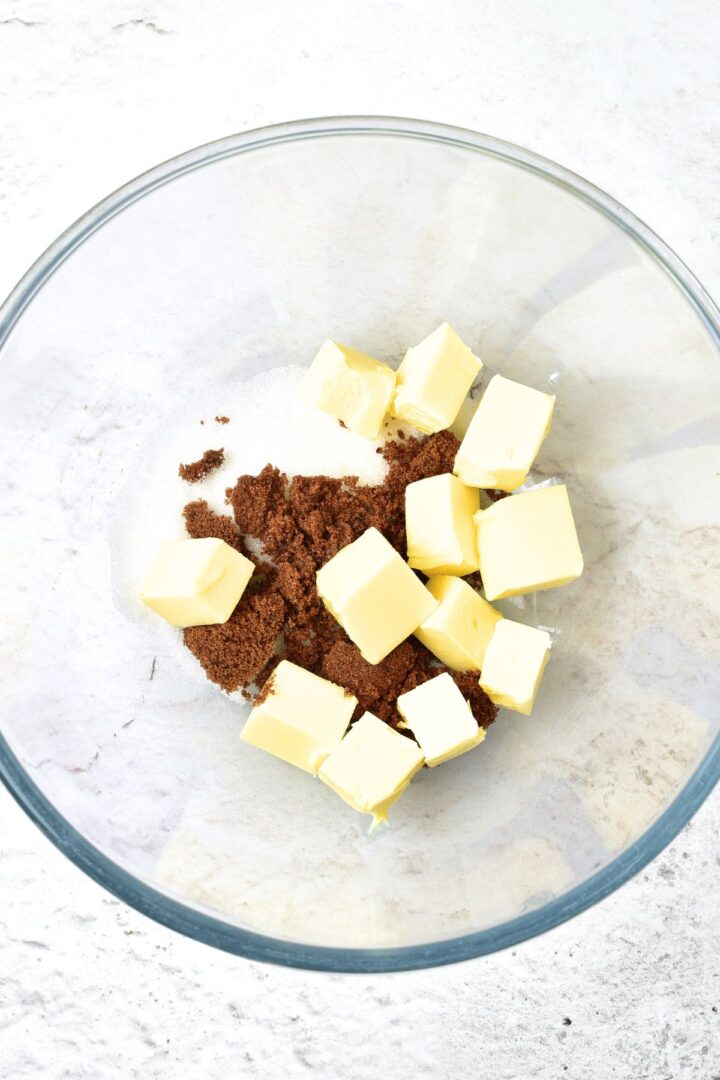 Brown sugar, white sugar and cubed butter in glass bowl.